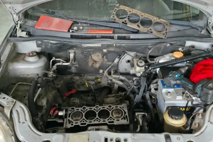 Silindir kapağı sökülmüş Chevrolet; eski kapak contası kaputun önünde